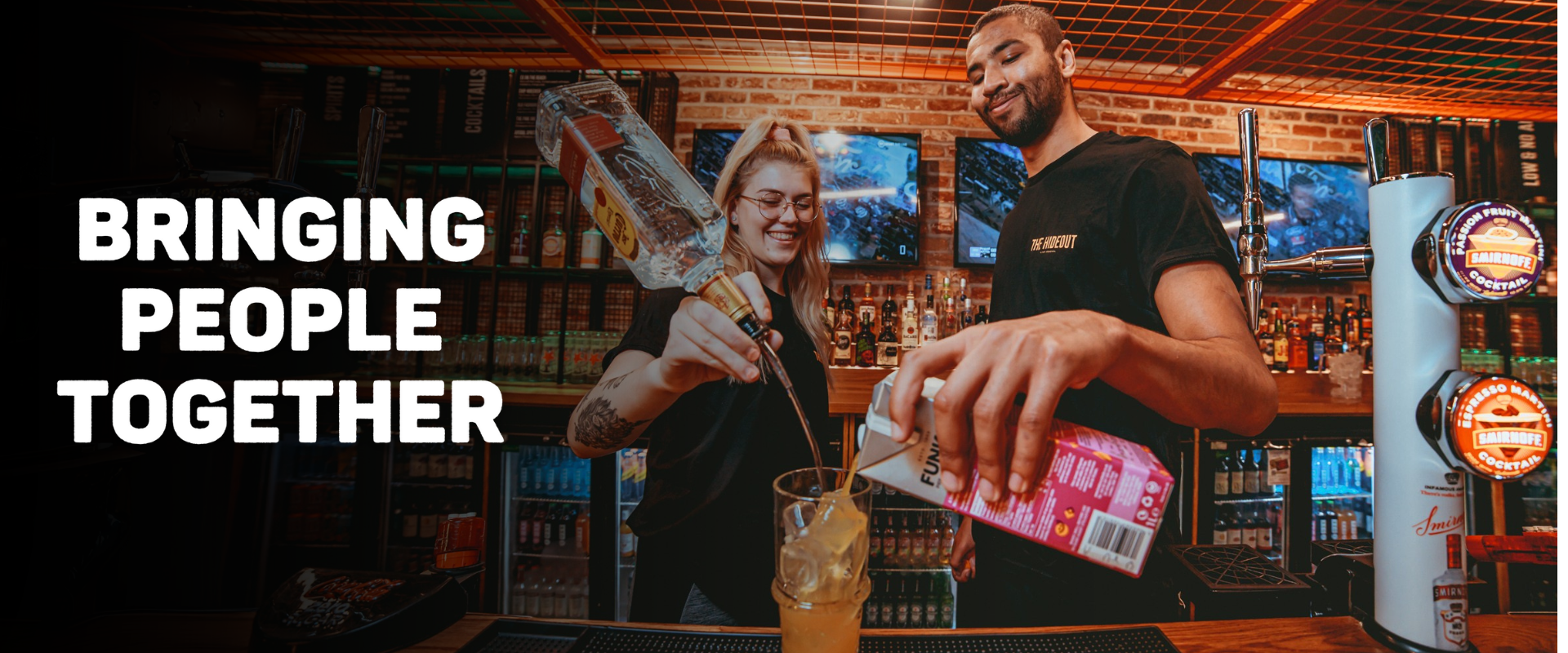 Image of two team members making a cocktail behind the bar.