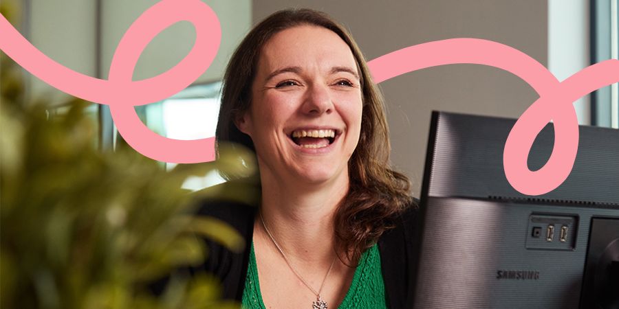 Woman sitting behind a computer screen, smiling