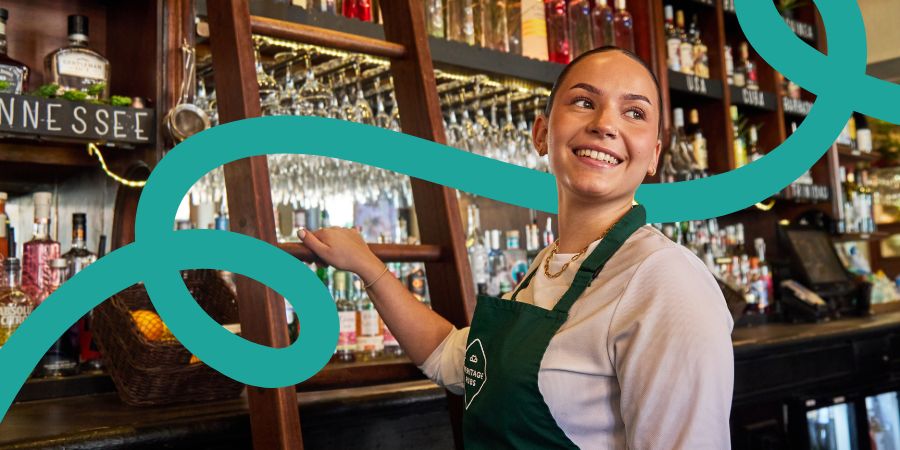 Smiling women behind bar with apron on
