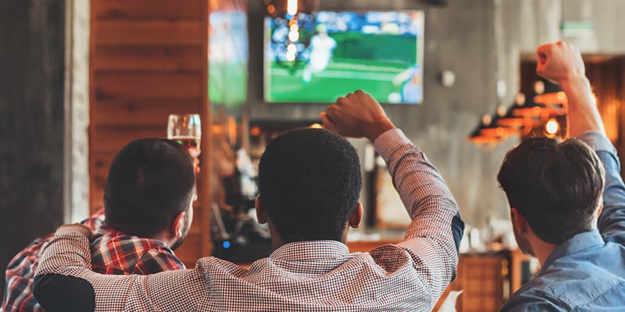 3 men watching football with a drink