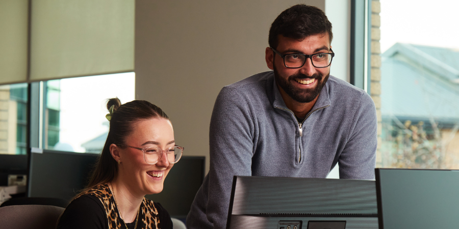 Two Pub Support Team members looking at a laptop