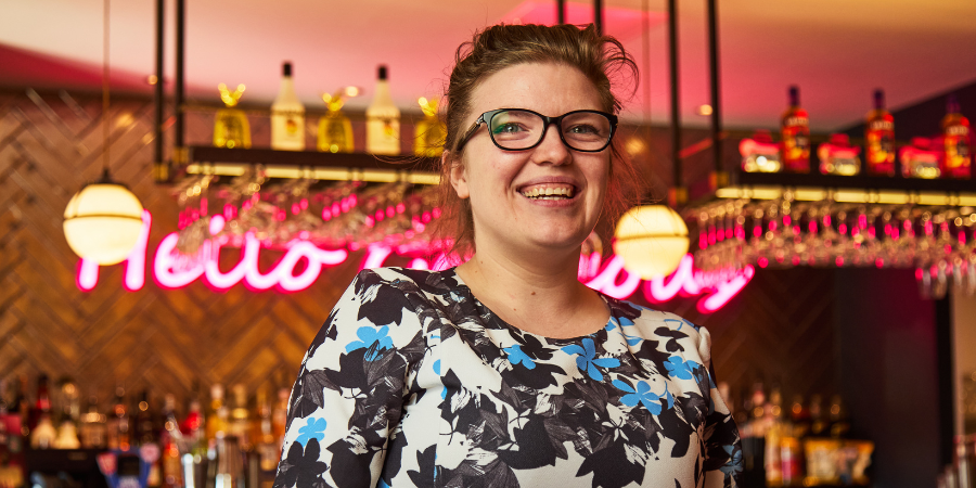 General Manager smiling in front of bar.