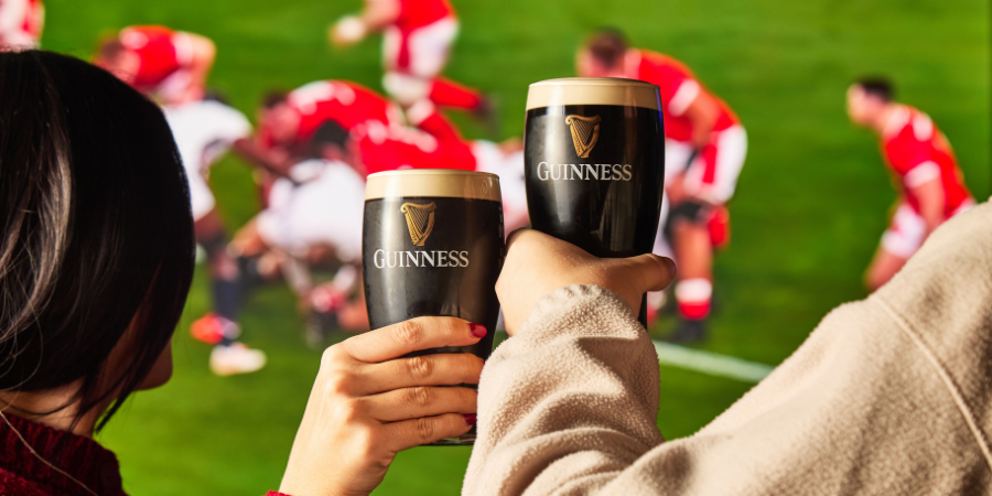2 PEOPLE WITH GUINNESS WATCHING RUGBY