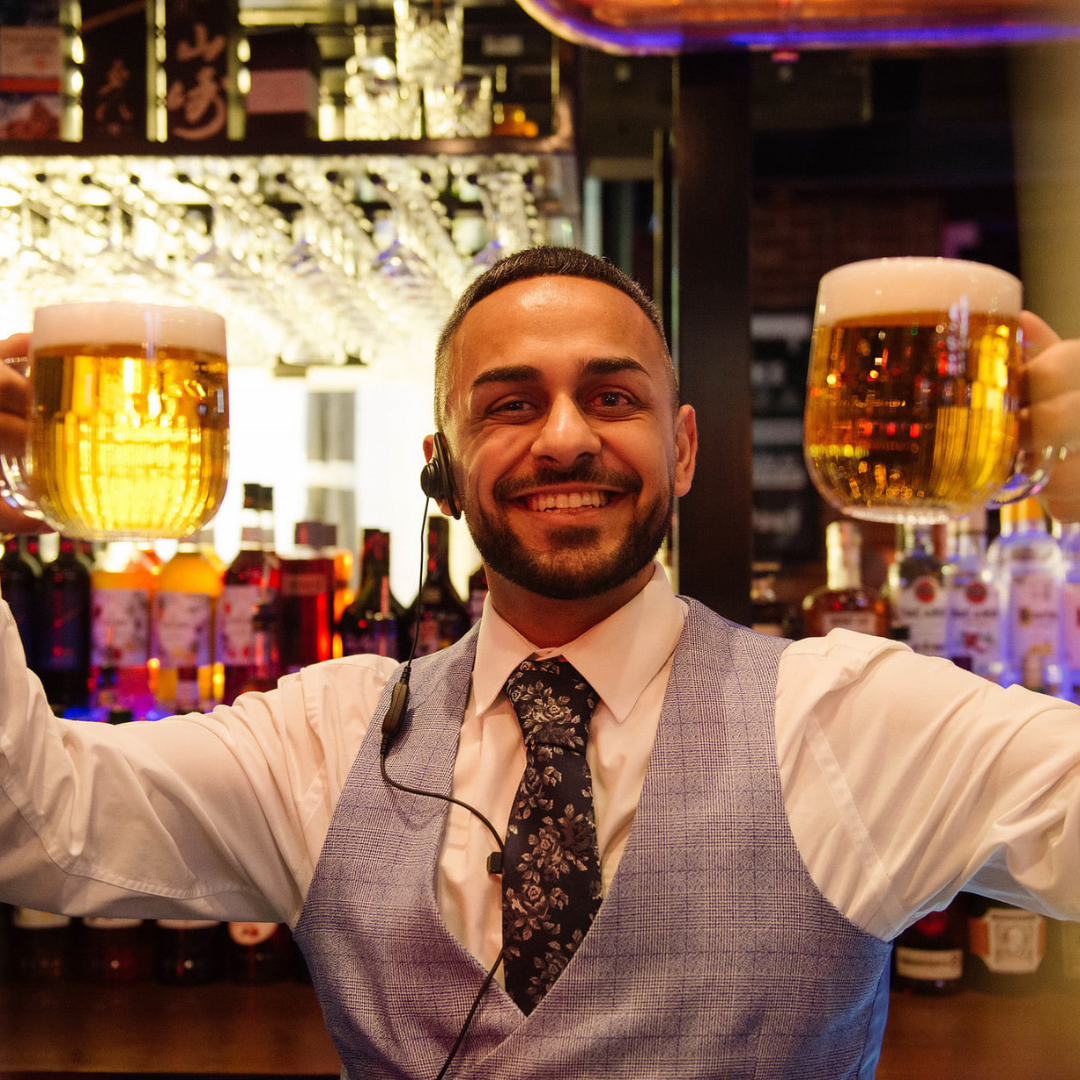 Employee holding up two pints and smiling at camera