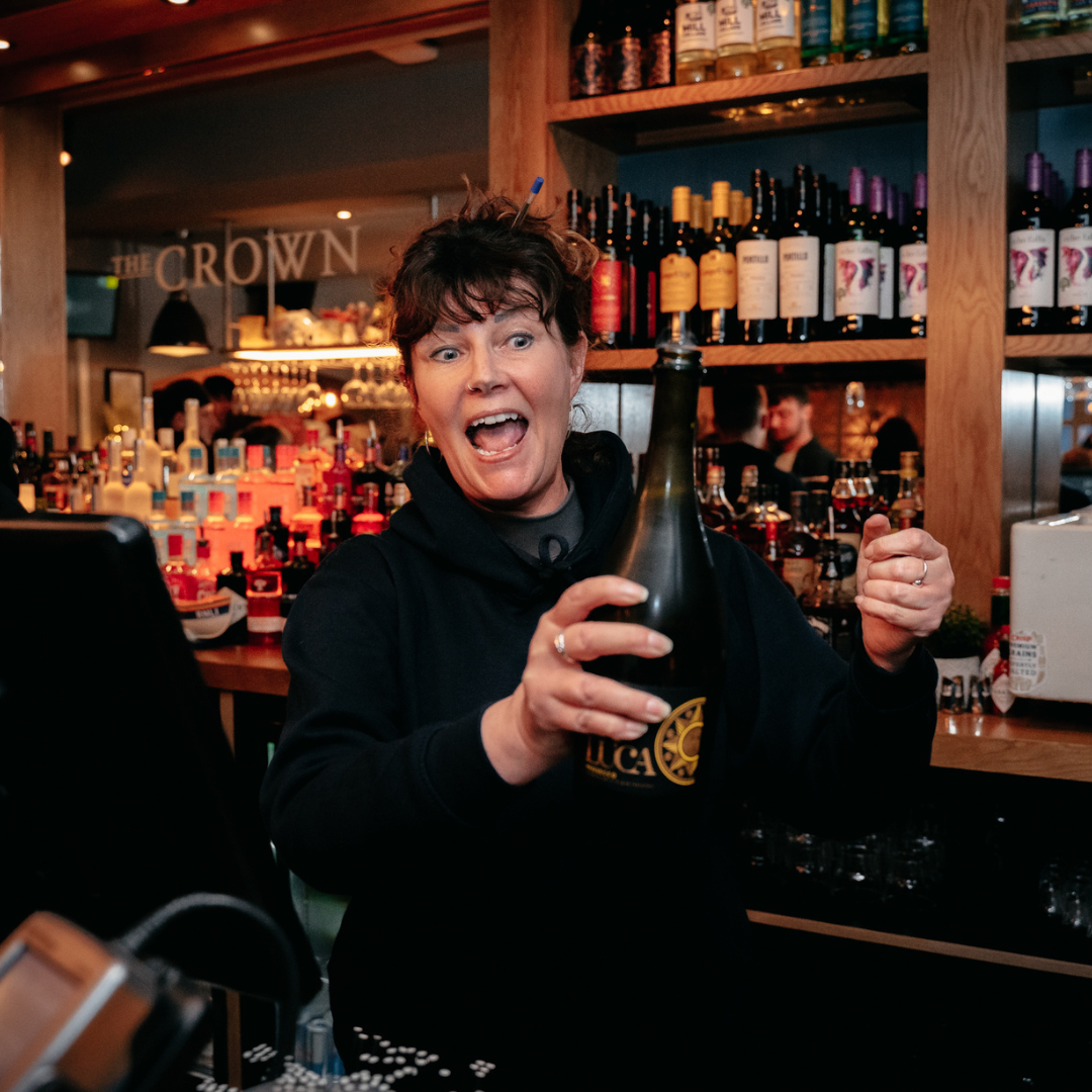 General Manager popping a bottle of prosecco