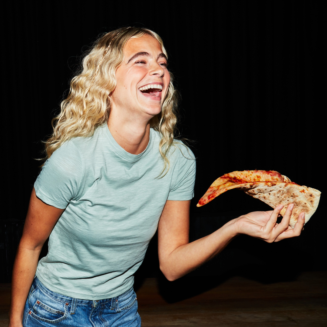 Woman enjoying slice of pizza at Rita's Woman enjoying slice of pizza at Rita's