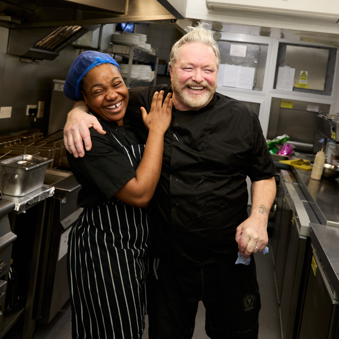 Image of a Kitchen Manager and Kitchen Team Member smiling to camera.