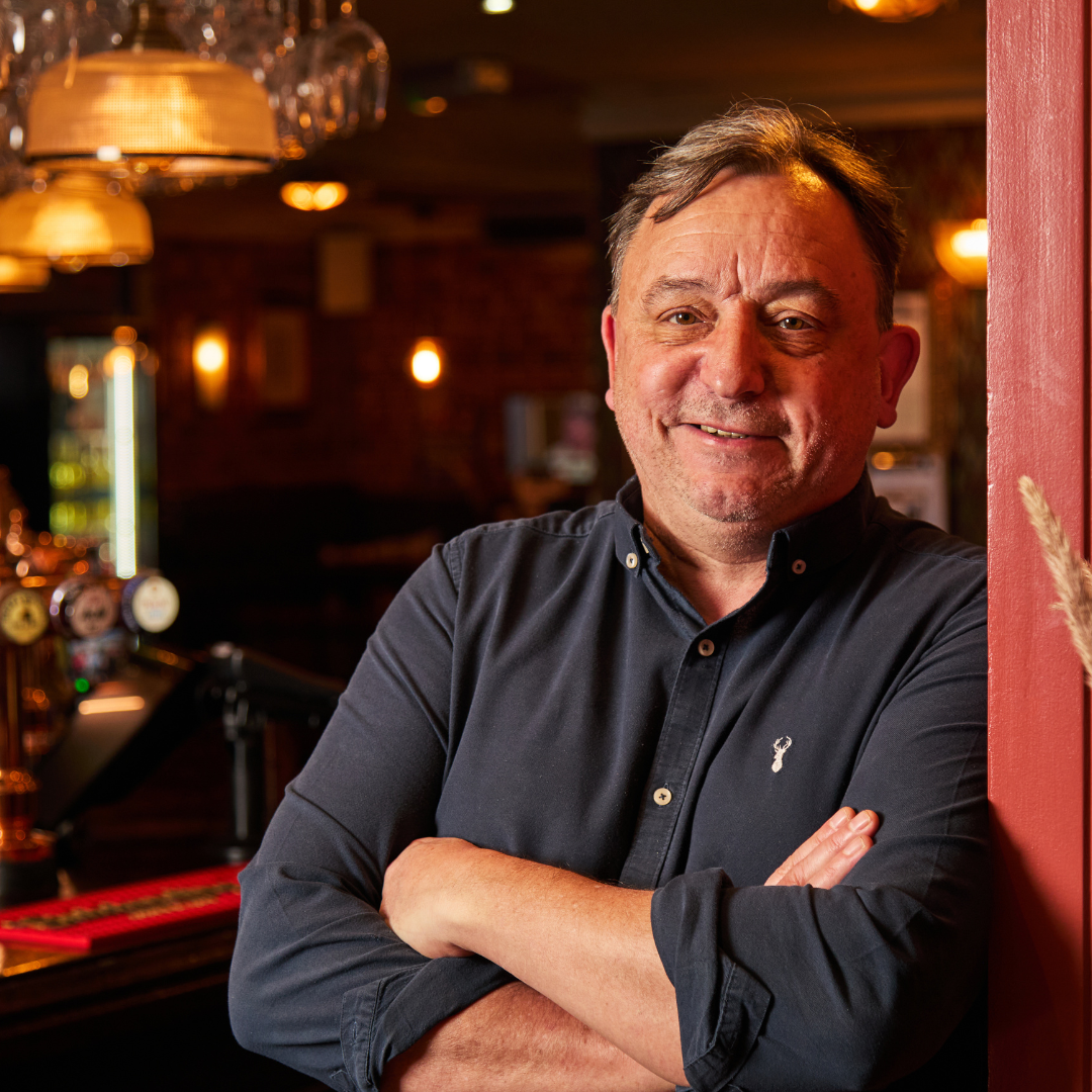 Pubsmiths General Manager smiling at the camera, arms crossed and leaning on a wall.