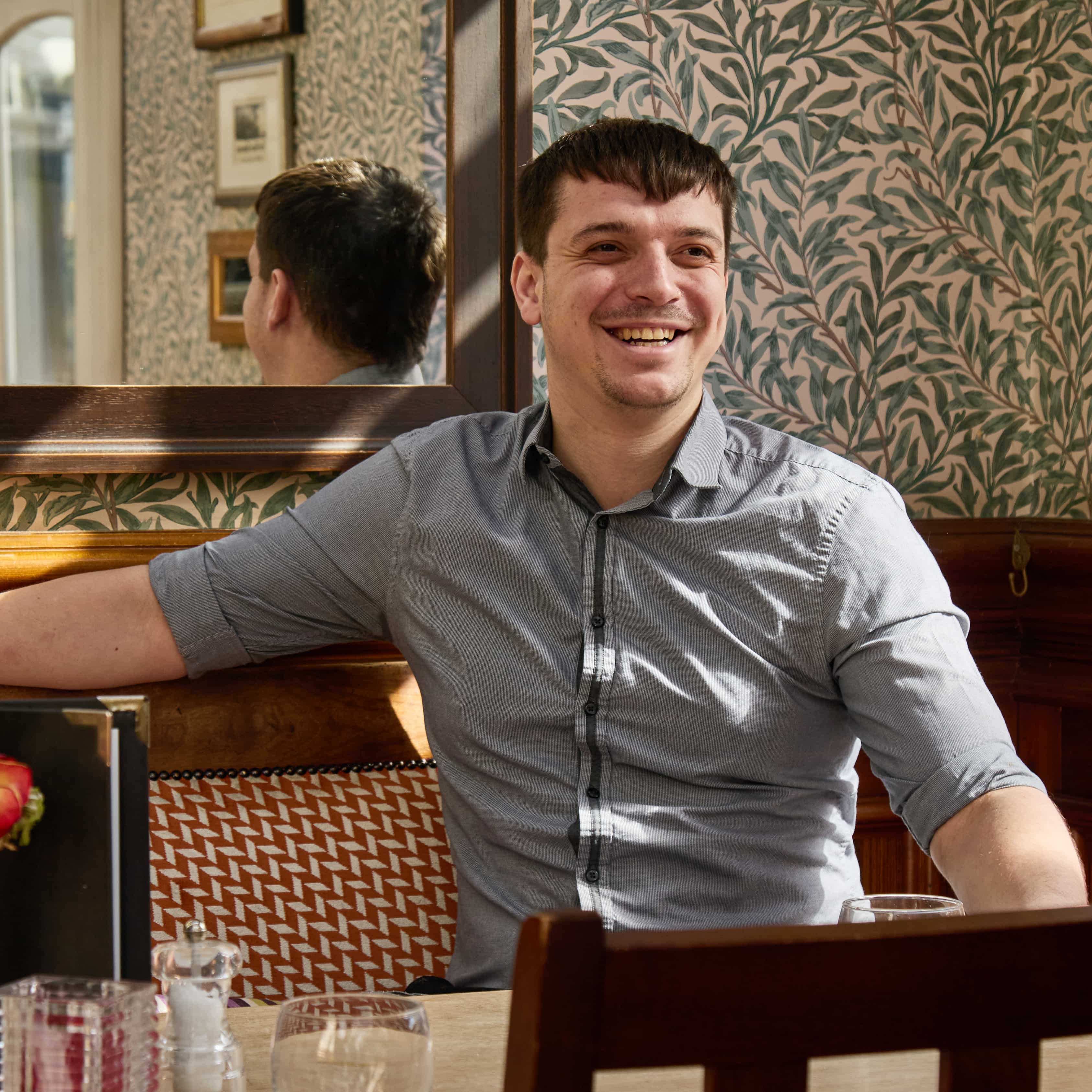 Image of Heritage DM smiling to camera while sat at a table.