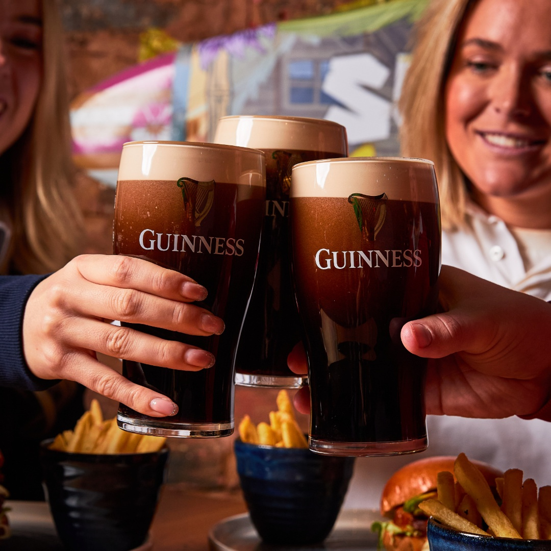 3 people cheersing Guinness