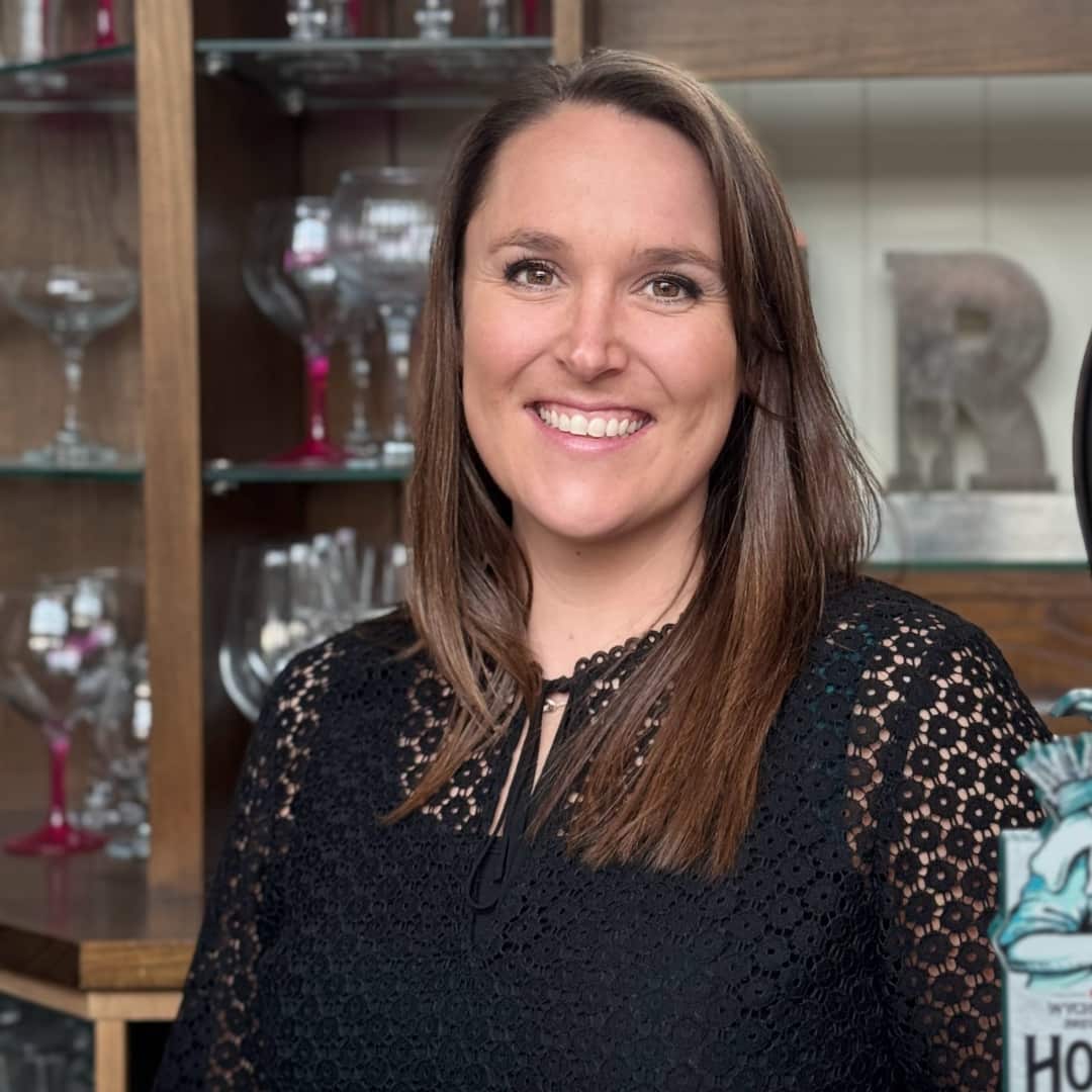 Image of Ashlie smiling towards the camera in front of shelves of glassware.