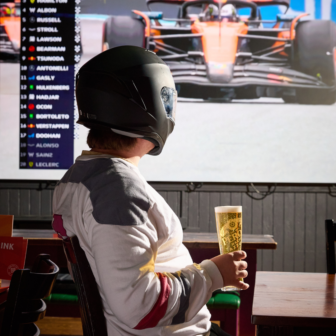 F1 fan watching grand prix with a pint