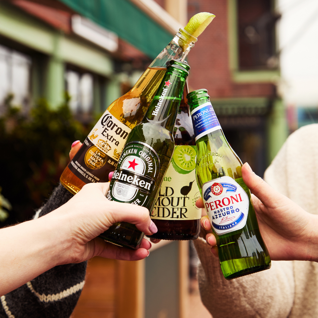 4 people cheersing assorted bottles of lager and cider