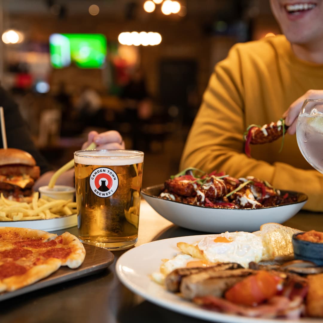 Brunch consisting of burgers, pizza, chicken wings and a breakfast with beer