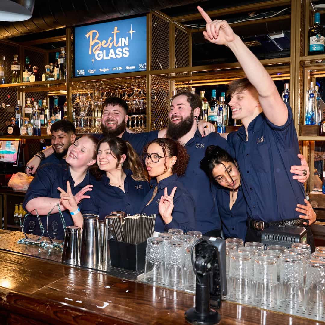 All contestants posing behind the bar.