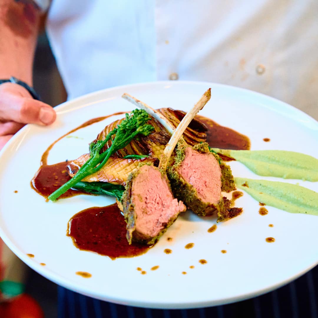 Image of a Masterchef dish including lamb chops and broccoli on a white plate.