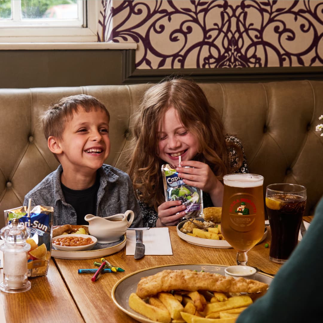 two children sitting at a table in a pub