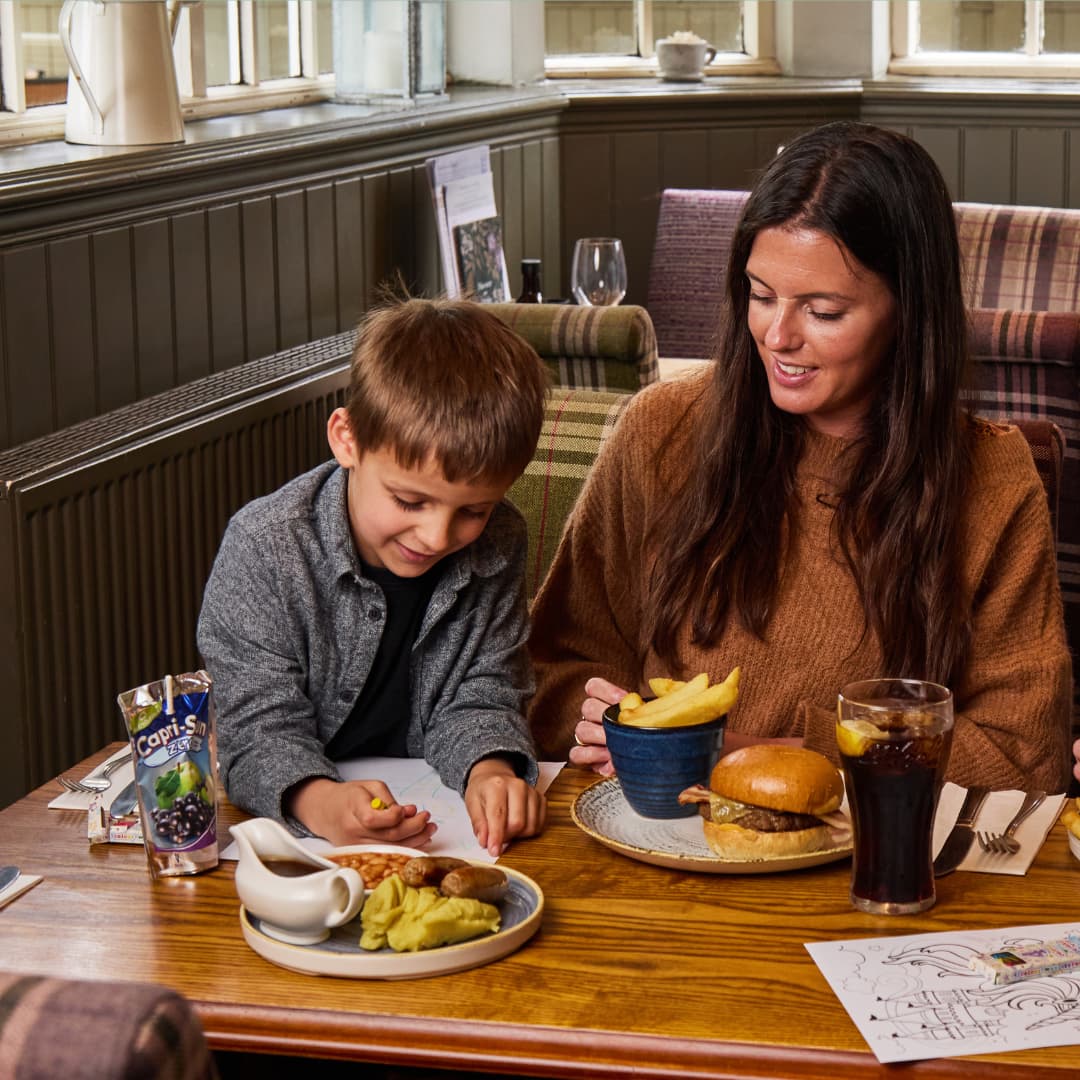 a child and parent colouring in at a table in a pub with food