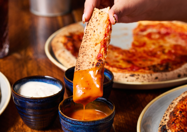 Dunking pizza crust into sauce Dunking pizza crust into sauce