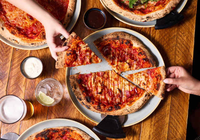 People grabbing a slice of pizza