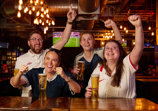 People cheering while watching the Euros with drinks