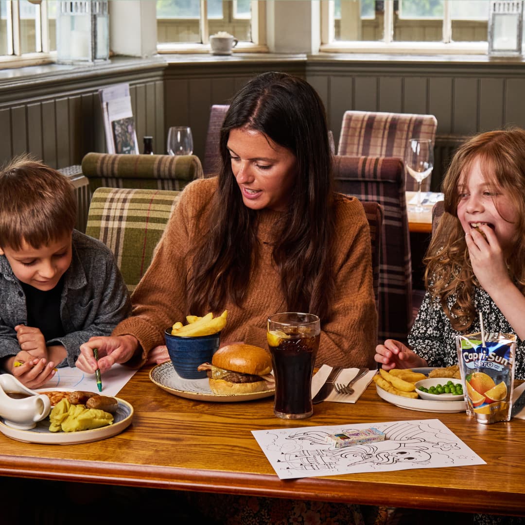 a parent and two children colouring and eating in a pub