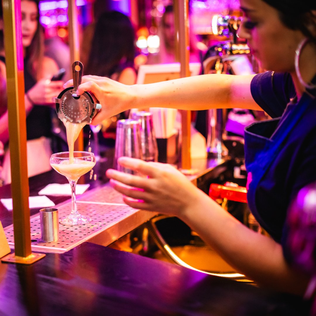 S&L bartender pouring a cocktail into a glass