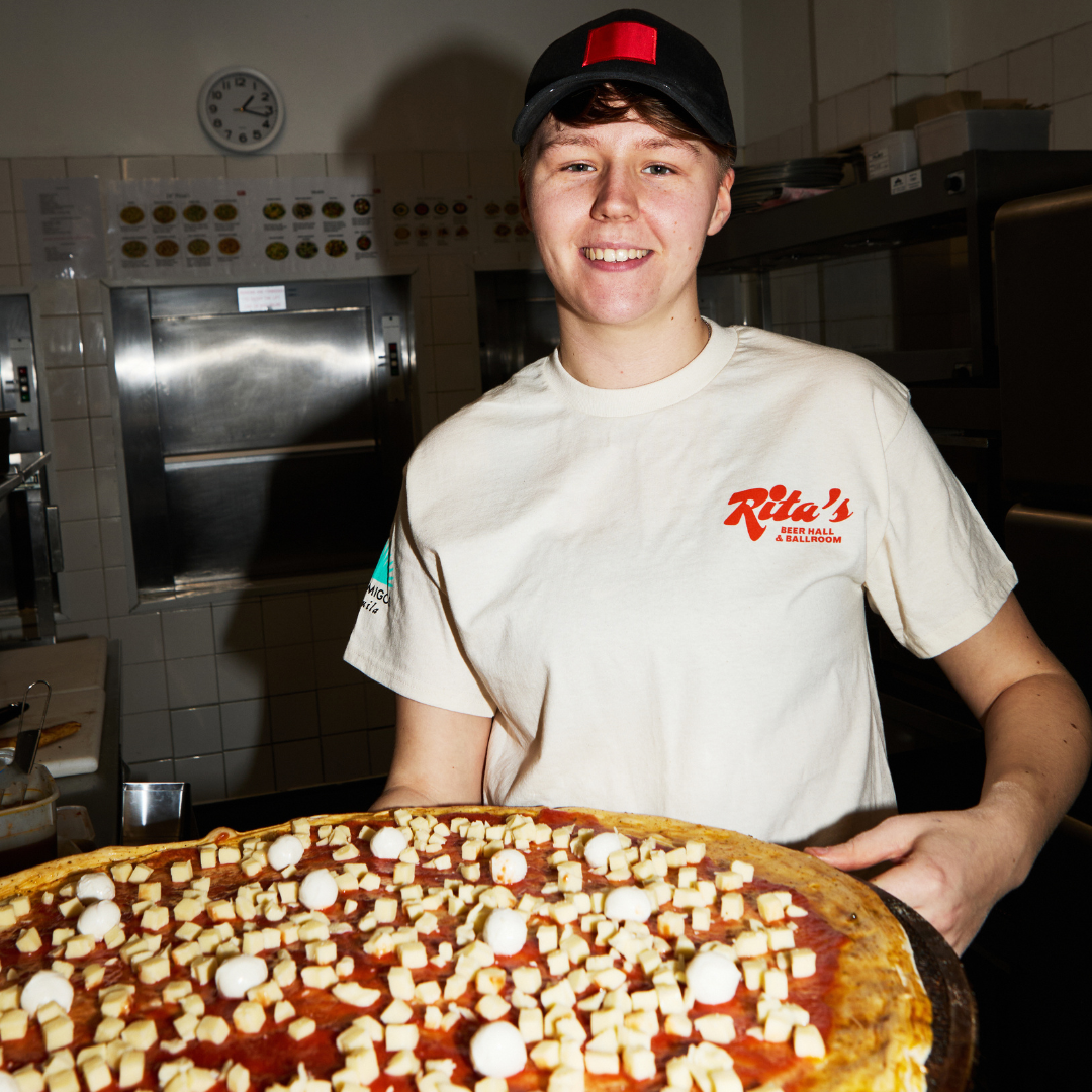 Rita's Kitchen Team Member with pizza.