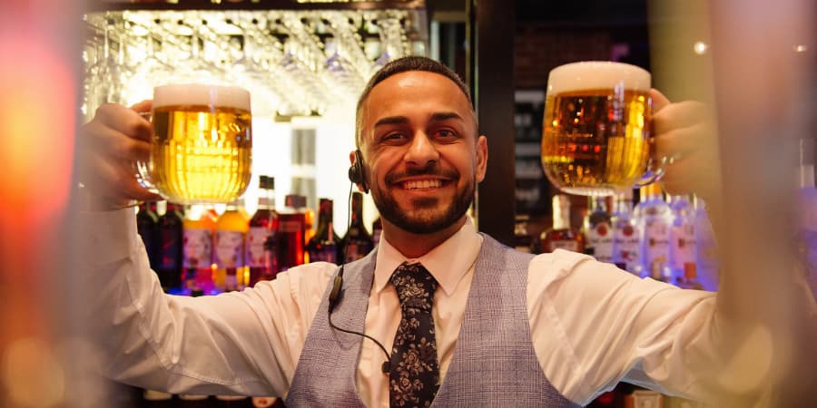 General Manager holding up two pints of beer.