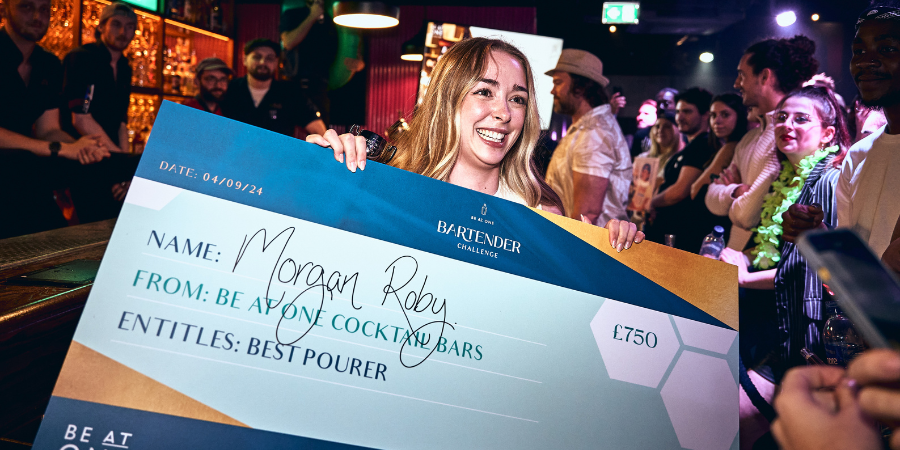 Best Pourer winner, Morgan smiling to camera holding a cheque