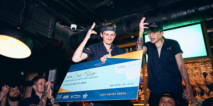 Sam holding his cheque behind the bar after winning Best Flairer