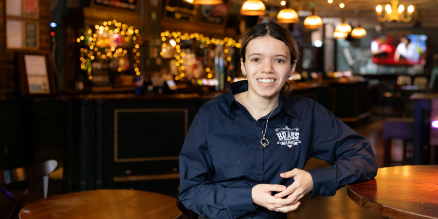 Team Member leaning on table smiling to camera.